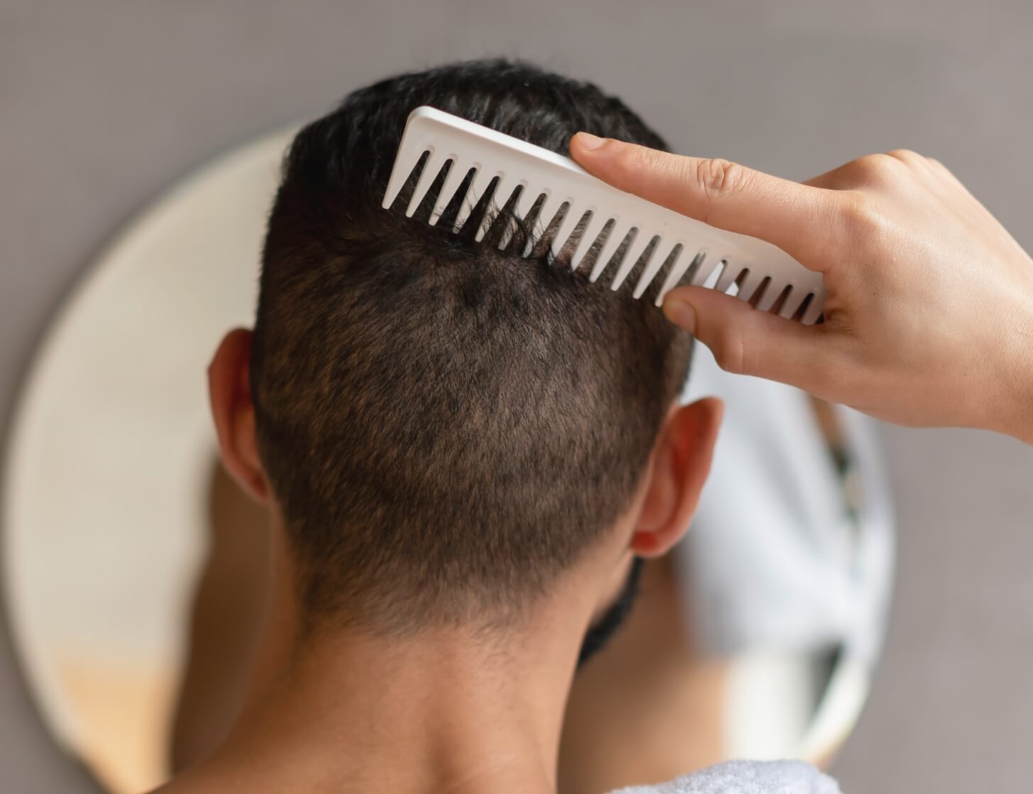 back-view-of-young-man-looking-in-mirror-brushing-2023-11-27-05-23-38-utc (1)