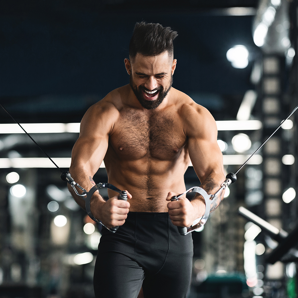 Strong muscular man training with block exerciser in gym